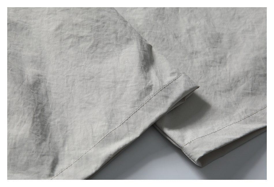 Close-up of the light gray shorts' stitched hems and softly crinkled fabric.