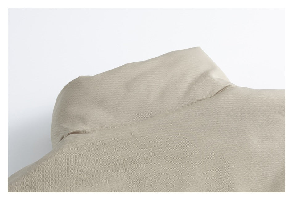 Close-up of the beige jacket's raised collar and smooth outer fabric.