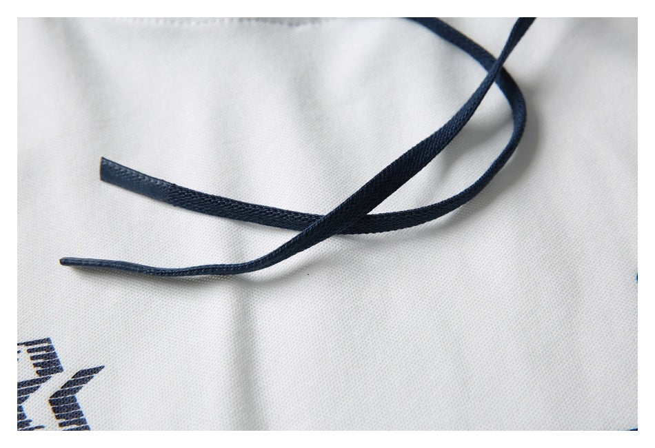 Close-up of two navy drawstrings crossing over white garment fabric.