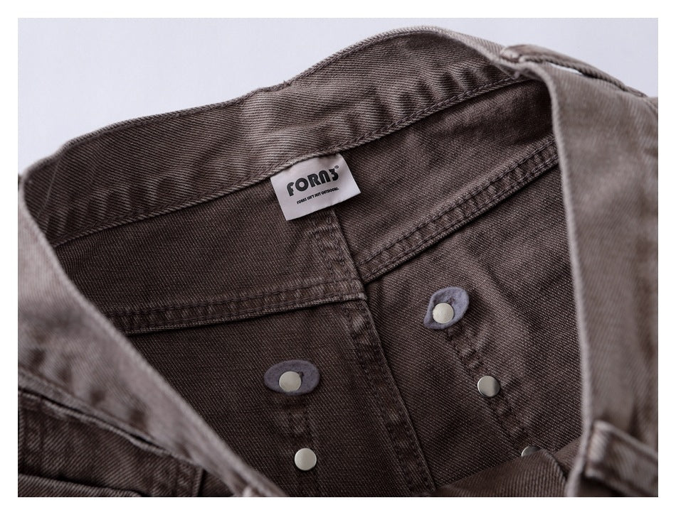 Inside waistband detail showing the sewn-in brand label and metal button hardware on the taupe jeans.