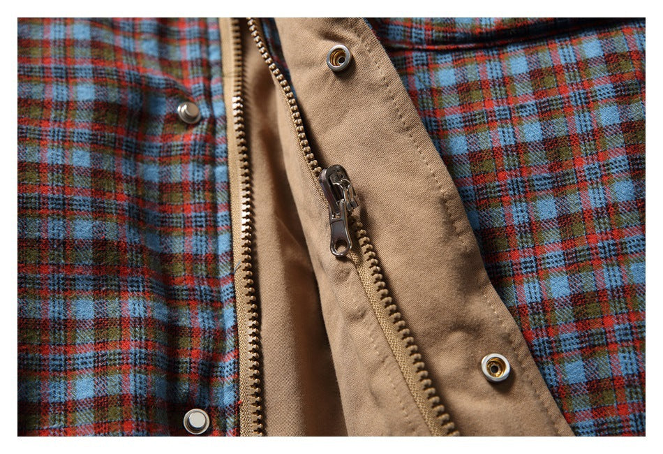 Close-up of a tan jacket zipper and snap placket against blue, red, and brown plaid panels.