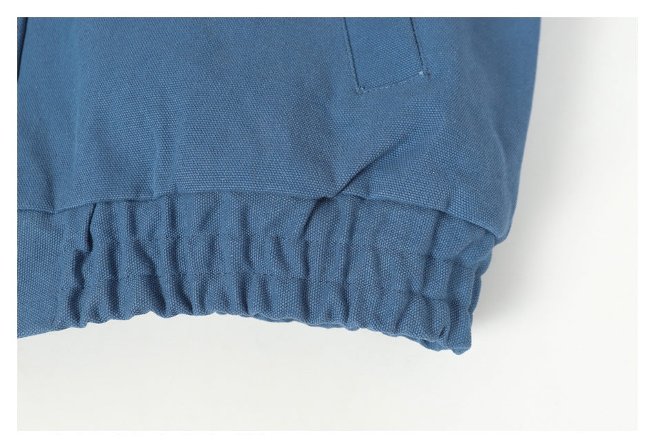 Close-up of the blue jacket's gathered elastic hem and stitched seam.