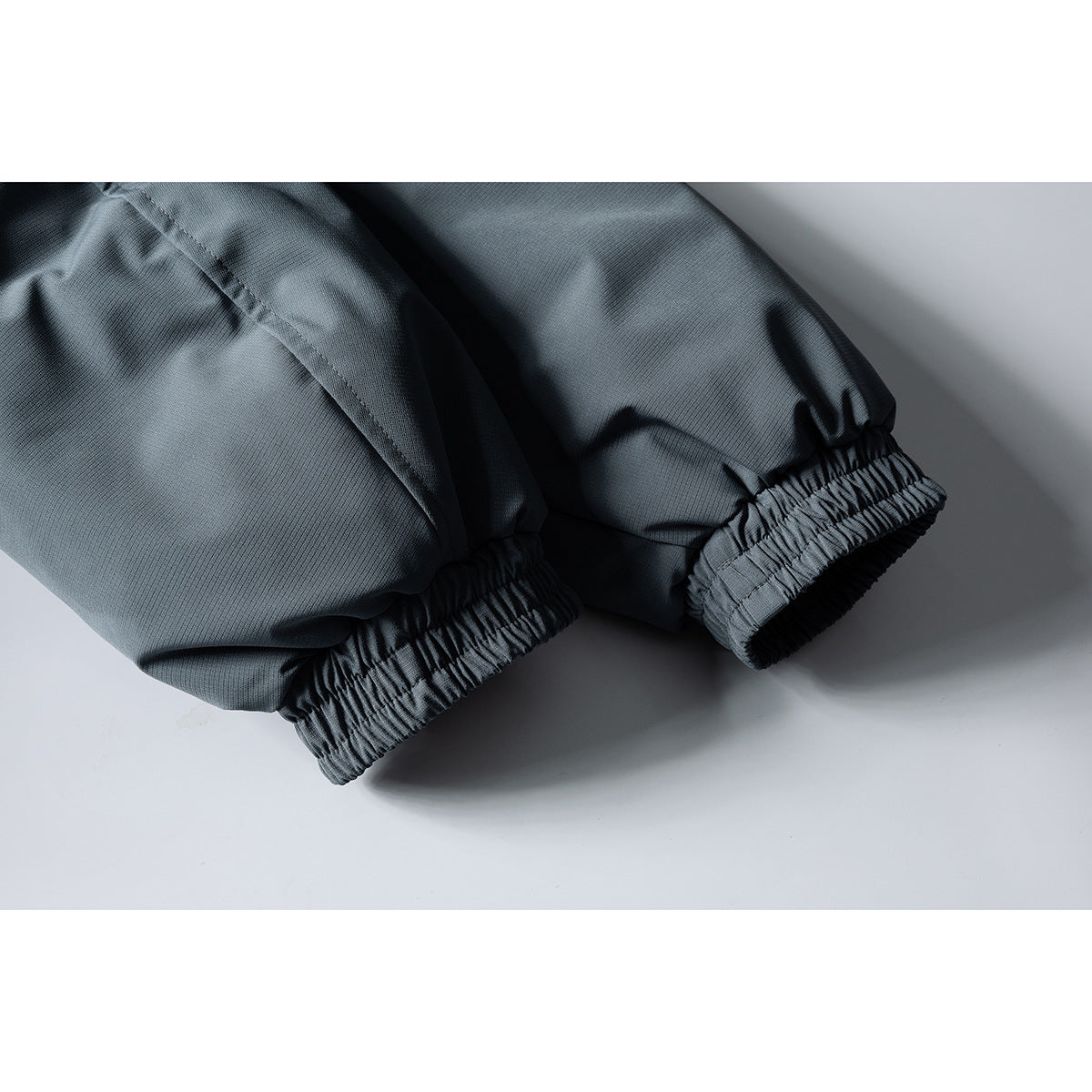 Close-up of the jacket's two gathered elastic sleeve cuffs in charcoal gray.