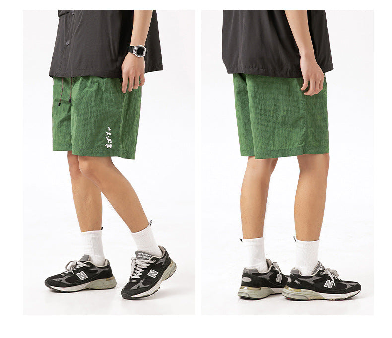 Cropped model shown from front and side wearing green drawstring shorts with a small white leg graphic.