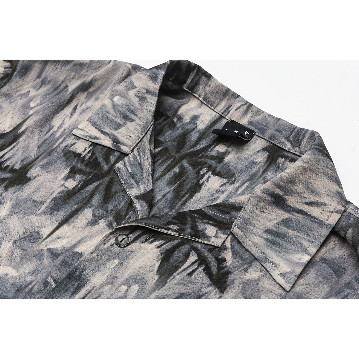 Close-up of a gray and black abstract-print shirt collar, lapel, and button.
