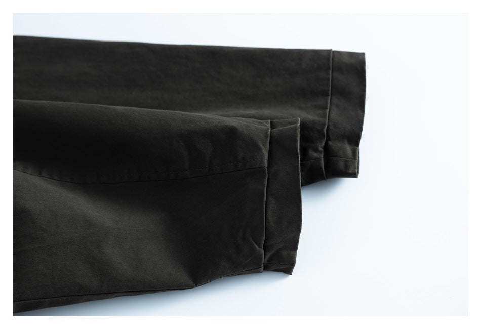 Close-up of two dark charcoal garment cuffs with folded hems against a white background.