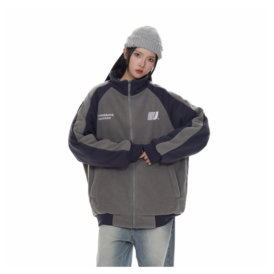 Person wearing the gray and navy zip-up jacket in a relaxed fit with a gray beanie and light jeans