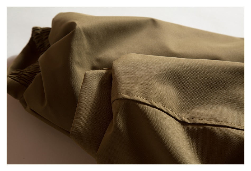 Close-up of a tan-brown garment seam and folded edge, with gathered elastic visible at the side.