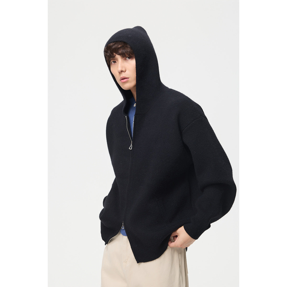 Model wearing a black hooded zip cardigan with oversized sleeves and a front zipper.