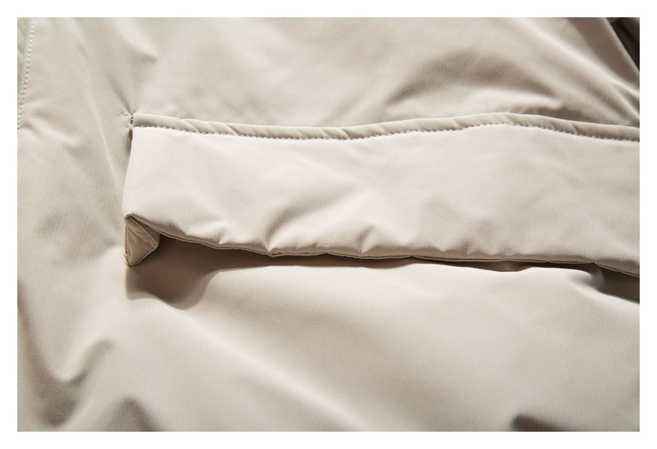 Close-up of a wide beige flap pocket and its stitched edge on the jacket.