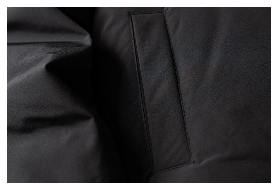 Close-up of a vertical rectangular welt pocket on black garment fabric.