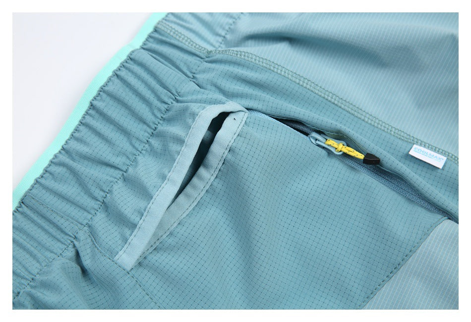 Close-up of blue shorts showing an open zip pocket, yellow zipper pull, and elastic waistband.