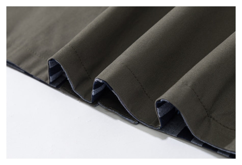 Close-up of the dark olive garment's hem, showing folded checked lining beneath the stitched edge.