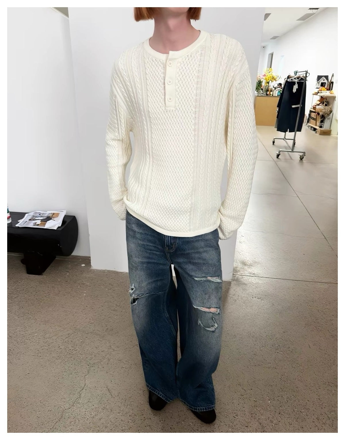Model wearing an ivory textured knit pullover with a button placket and distressed blue jeans.