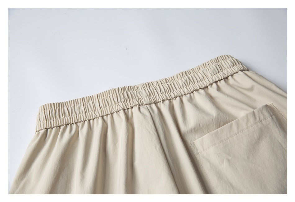 Close-up of cream shorts with a gathered elastic waistband and part of a rear pocket.