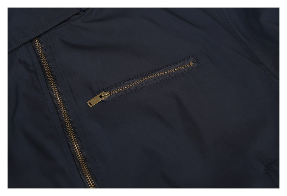 Close-up of the navy jacket's brass-tone zippered chest pocket and front zipper.