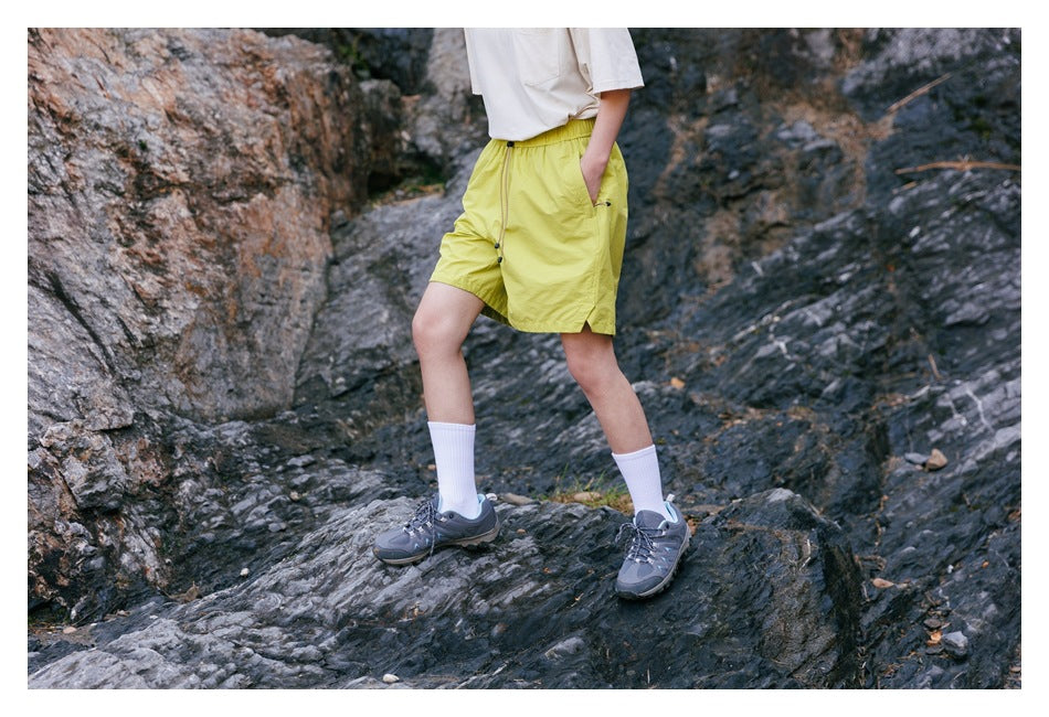 Angled view of a model wearing bright yellow-green shorts with an elastic waist, drawstring, and side pockets.