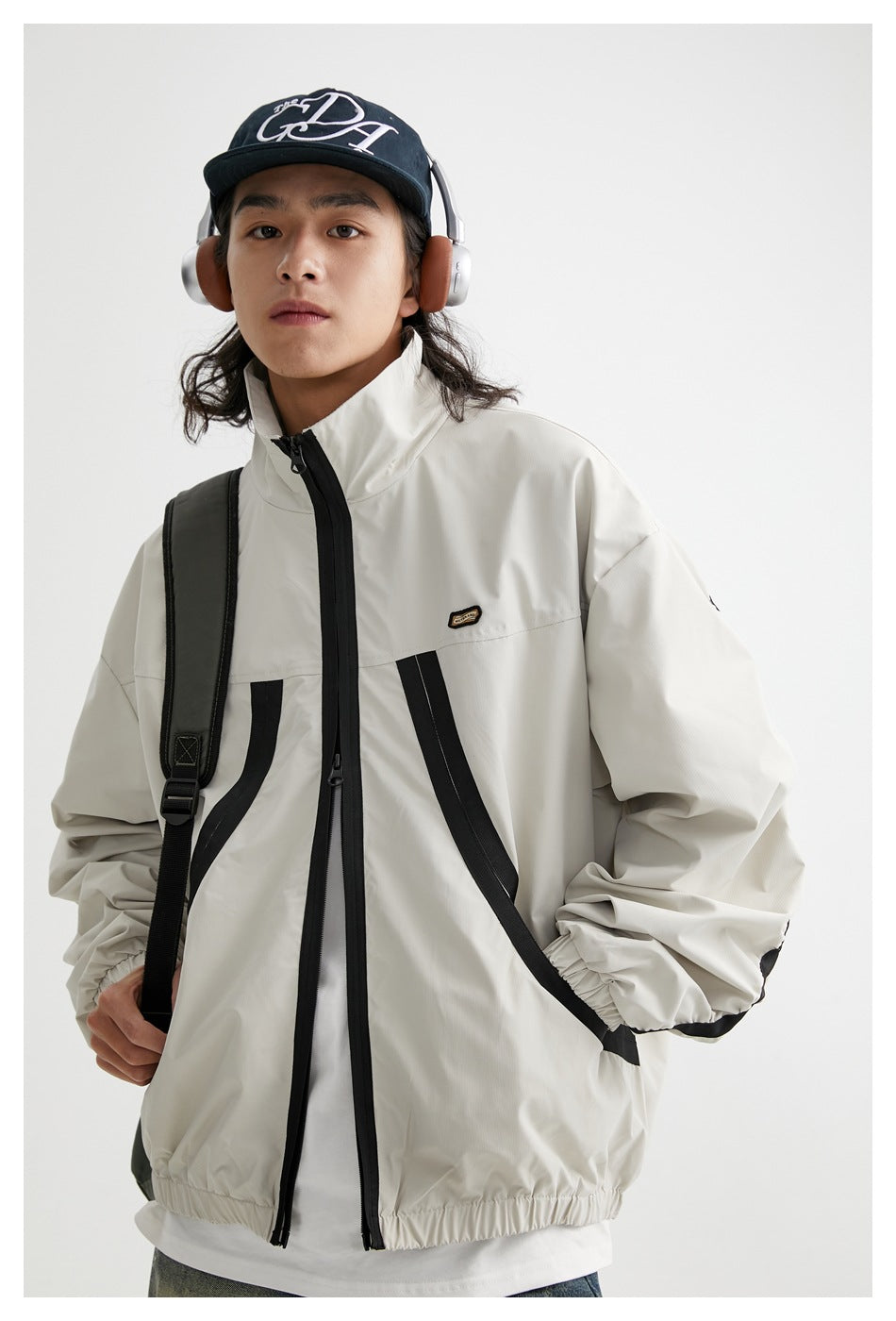 Model wearing an off-white zip-up jacket with black curved accents, elastic cuffs and hem, and a raised collar.