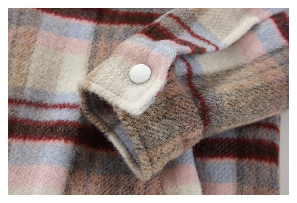 Close-up of a coat cuff with a round light-colored button and plaid fabric.