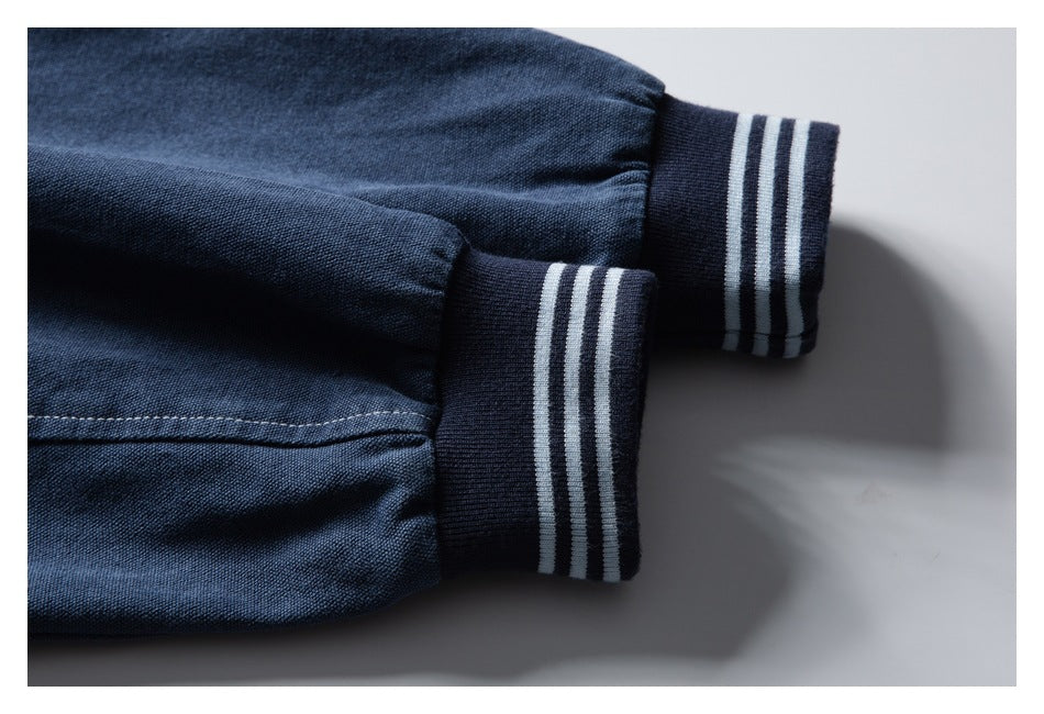 Close-up of two dark navy sleeve cuffs with white stripe detailing on ribbed trim.