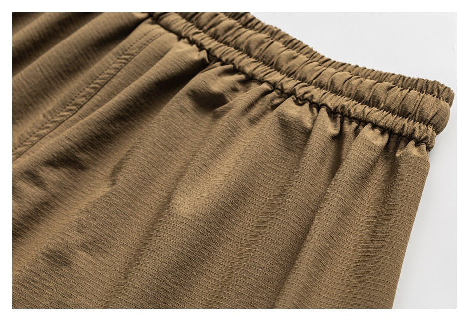 Close-up of the gathered waistband and fine surface texture of tan shorts.