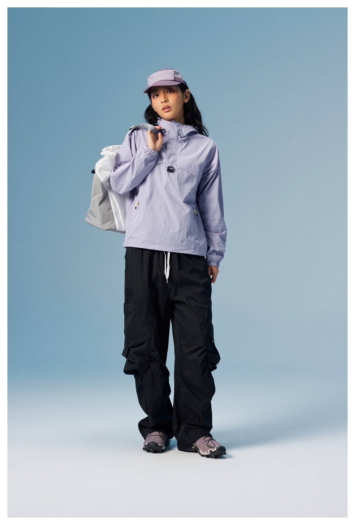 Model wearing a lavender hooded pullover, black cargo trousers, and a two-tone cap.