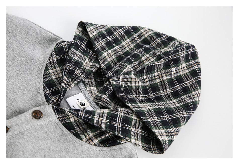 Close-up of a green, black, and cream plaid hood beside the gray top's buttoned neckline.