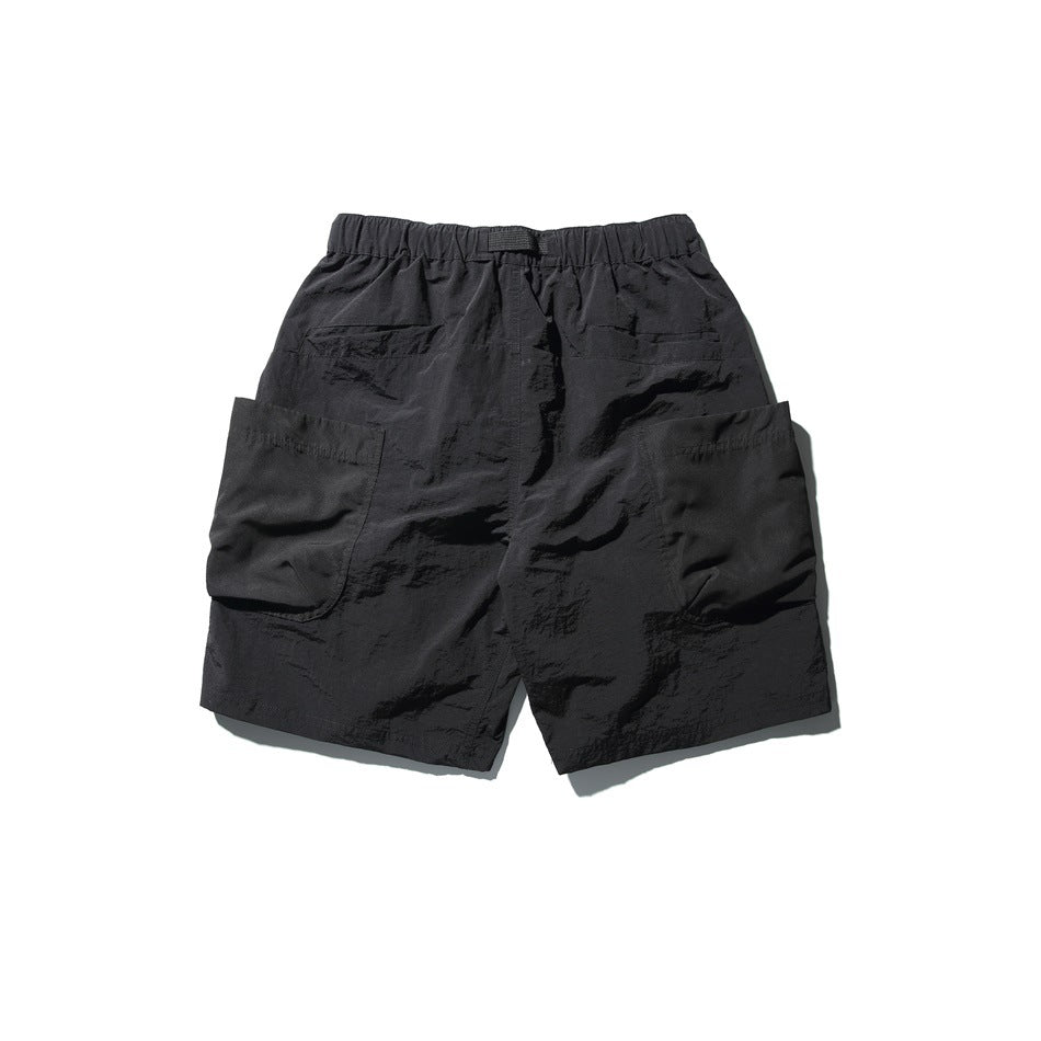 Back view of black utility shorts with elastic waist, back pocket detail and large side patch pockets, flat lay