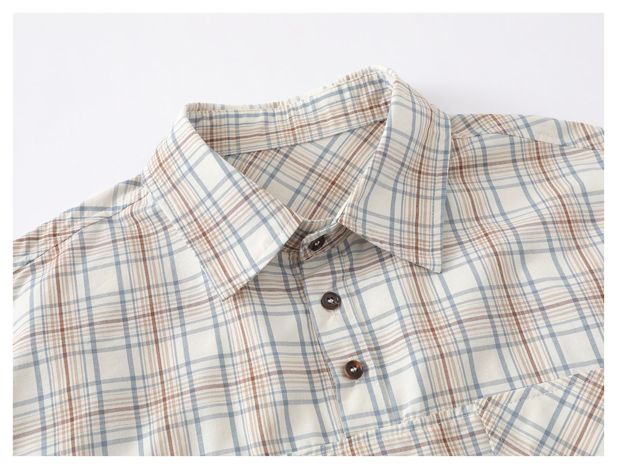 Close-up of a cream plaid shirt collar and brown buttons, with blue-gray and rust lines.