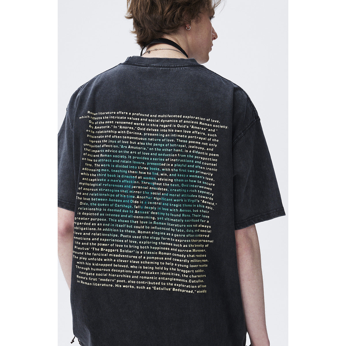 Close rear view of a model wearing a dark washed T-shirt with a large block of English text printed on the back.
