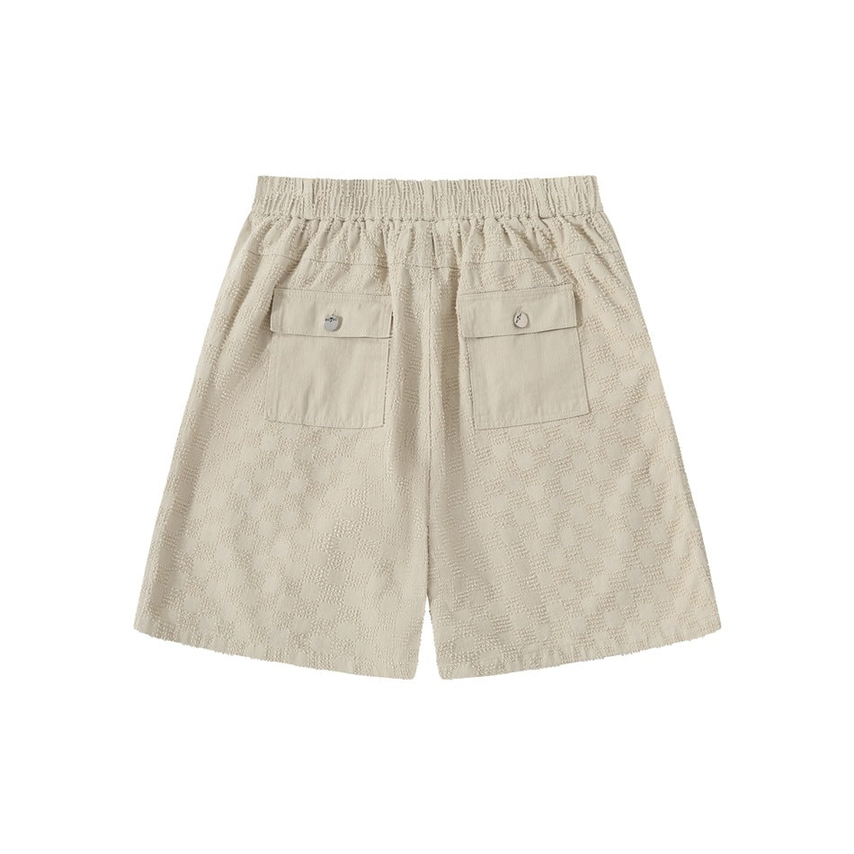 Back view of cream checker-pattern shorts with an elastic waistband and two flap pockets.