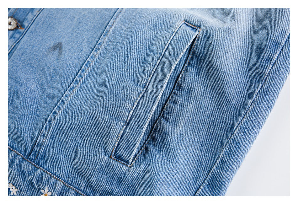Close-up of a narrow welt pocket on the sleeve of a blue denim jacket.