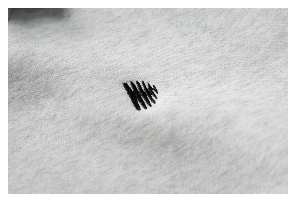 Close-up of light gray heather fabric with a small black stitched mark.