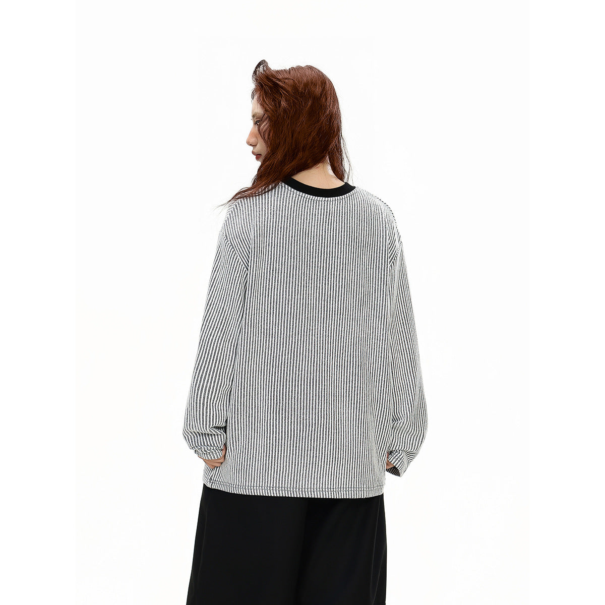 Back view of a model wearing an oversized white and gray vertically striped top with a black neckline.