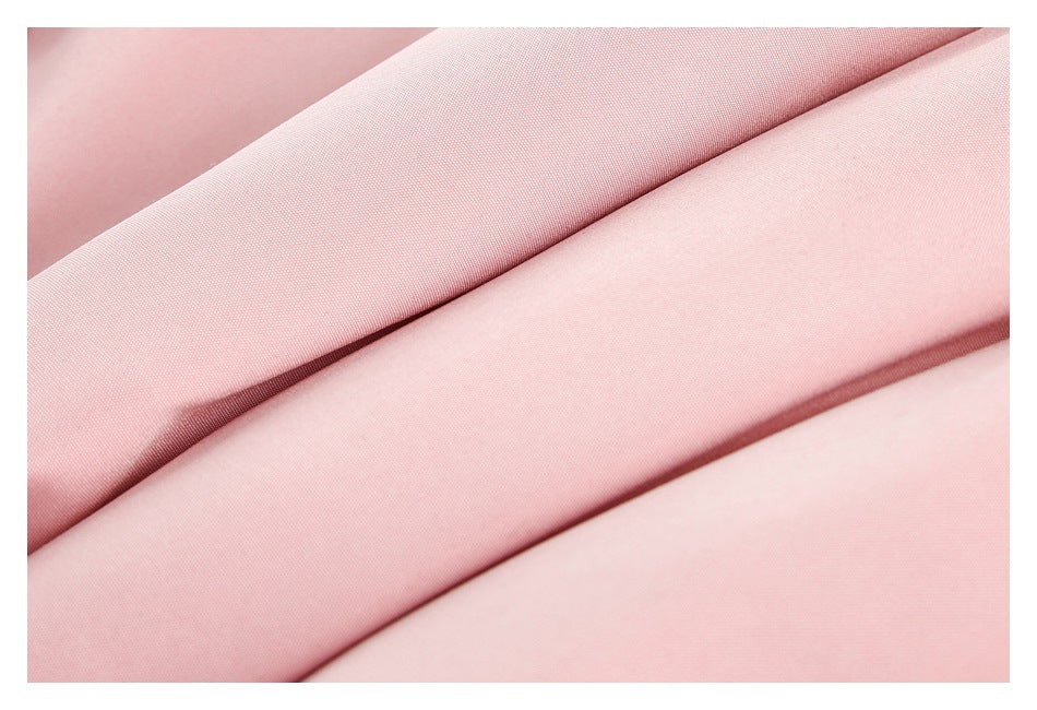 Extreme close-up of folded pale pink fabric showing its fine surface texture.