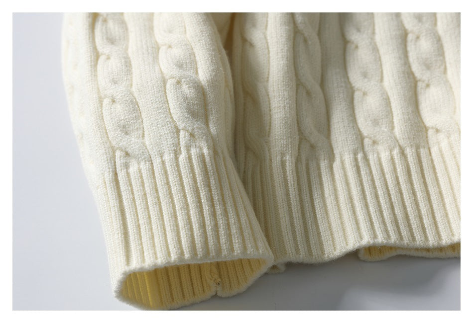 Close-up of an ivory cable-knit sweater sleeve and ribbed cuff.