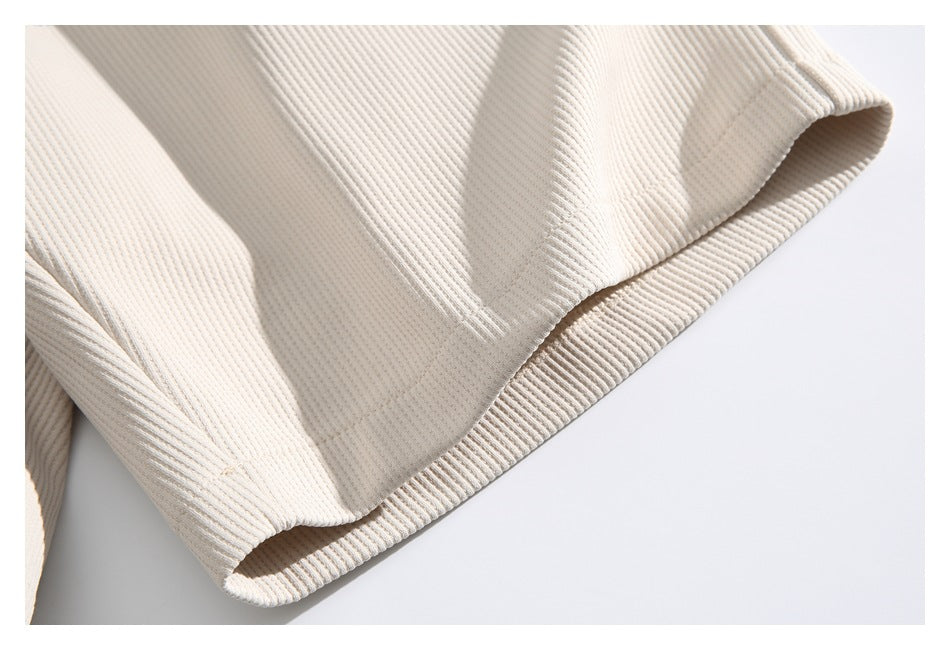 Close-up of a cream ribbed garment hem with a folded, stitched edge.