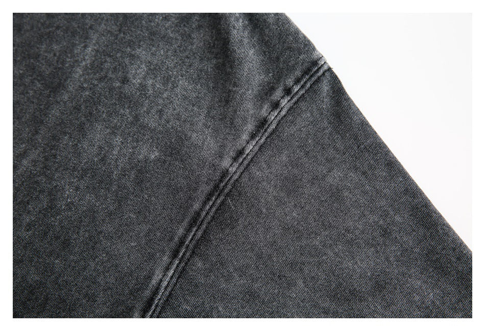 Close-up of a dark charcoal garment shoulder and sleeve seam against a white background.