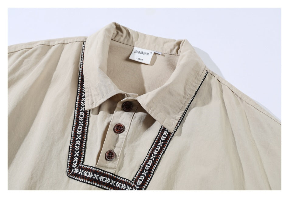 Close-up of a beige shirt collar and button placket framed by black, white, and rust geometric trim.