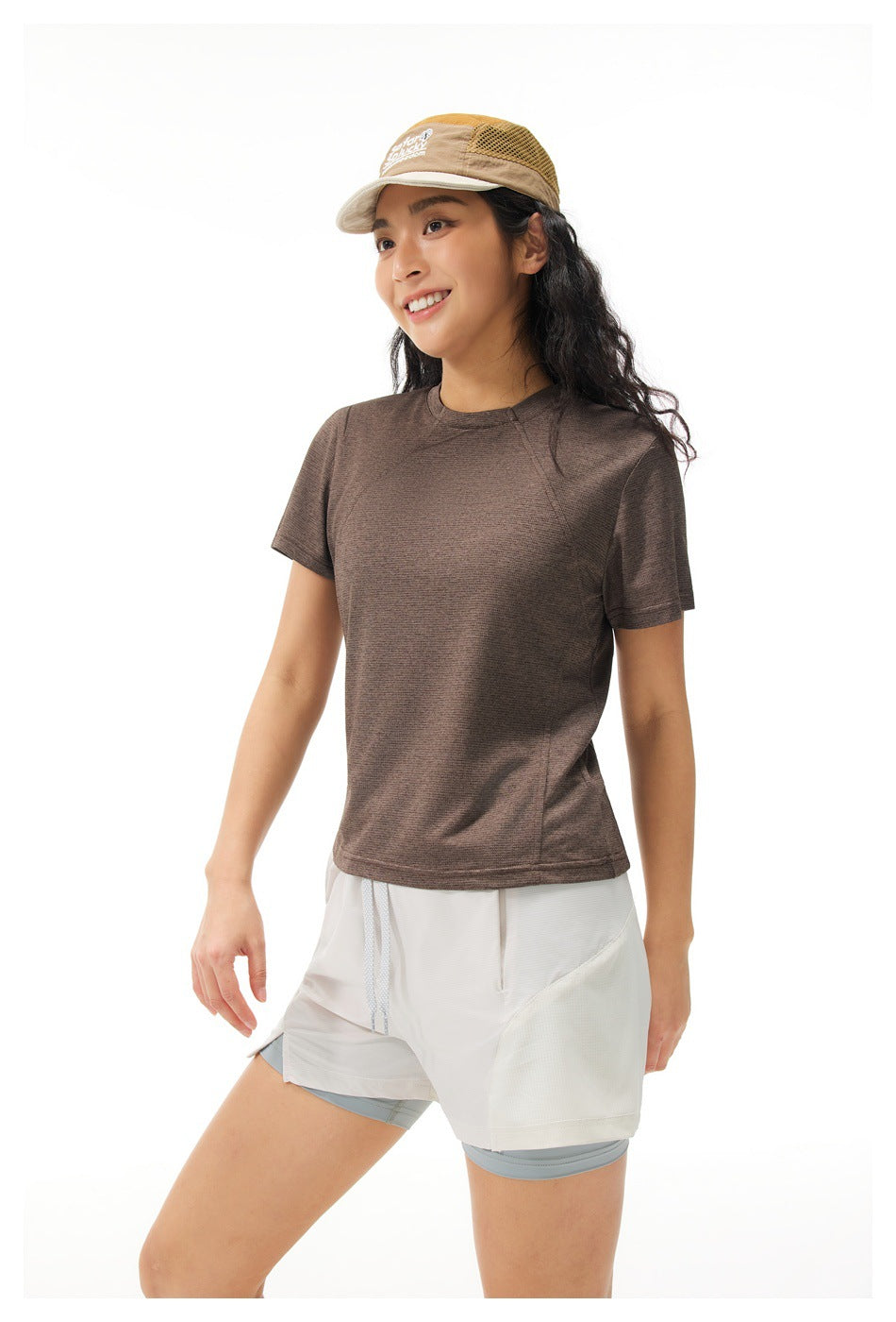 Front view of a model wearing a brown short-sleeve athletic shirt and layered white shorts.