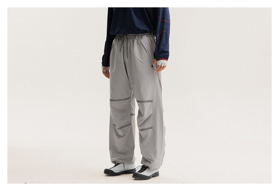 Cropped model wearing loose light-gray drawstring pants with dark horizontal bands across the legs, shown from a front-side