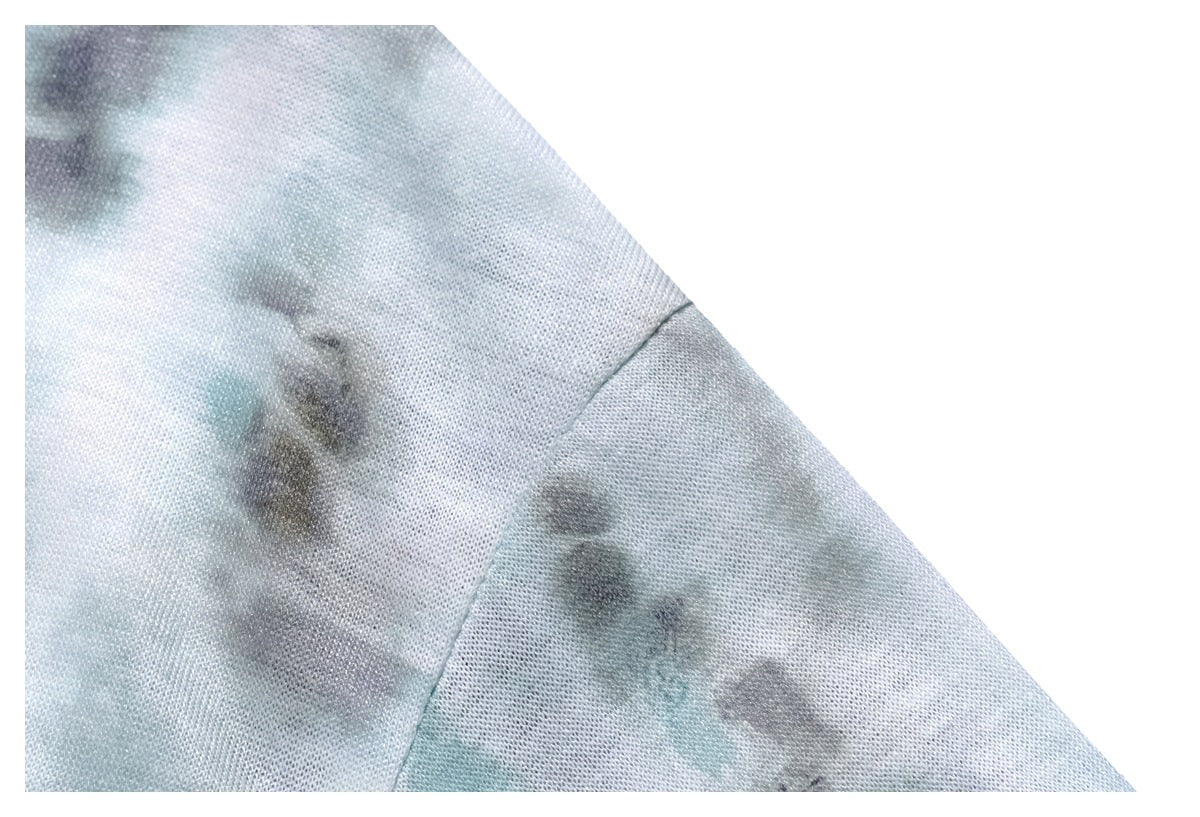 Close-up of the tie-dye fabric and seam on a pale blue-gray sleeve.