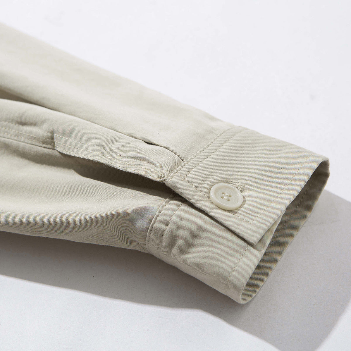Close-up of a light beige jacket sleeve cuff with a button fastening.