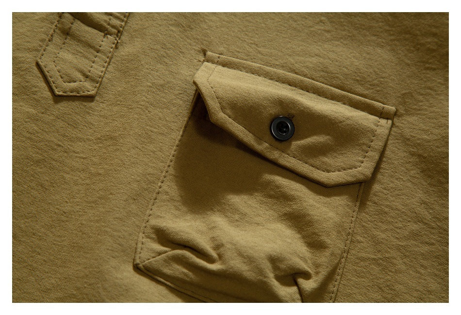 Close-up of a tan garment with a large button-flap pocket and a small stitched tab.