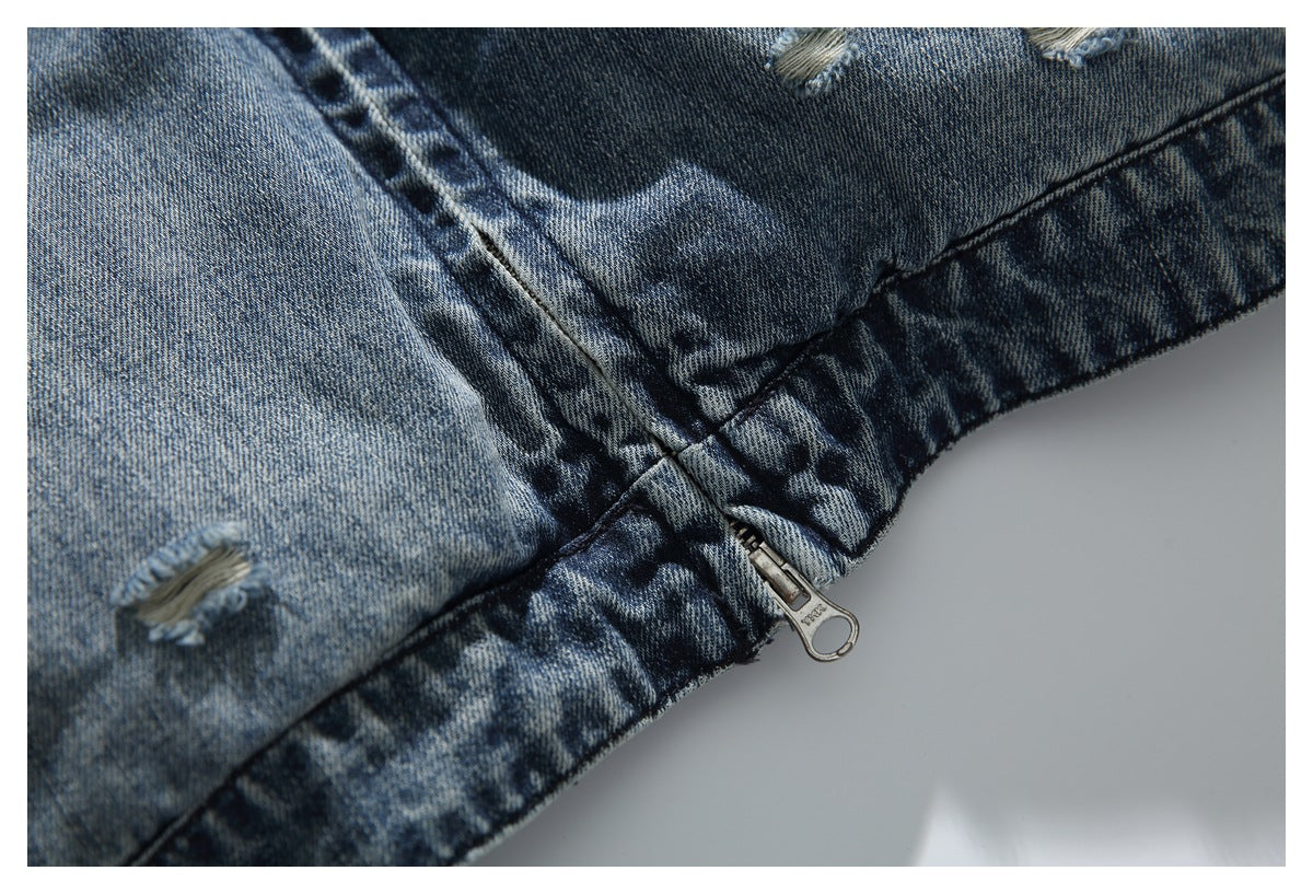 Close-up of a distressed blue denim jacket with a metal zipper and faded, frayed areas.