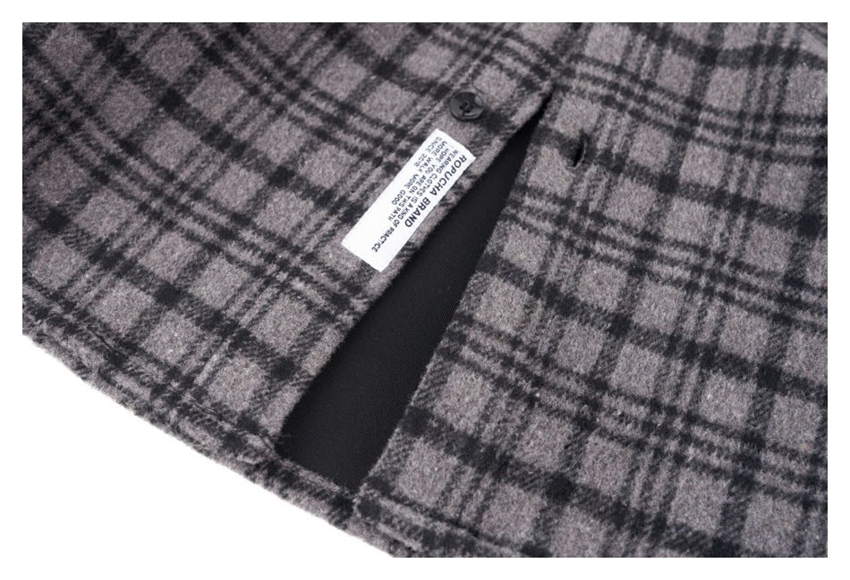 Gray and black plaid garment opening with a black button, dark lining, and a small sewn label.