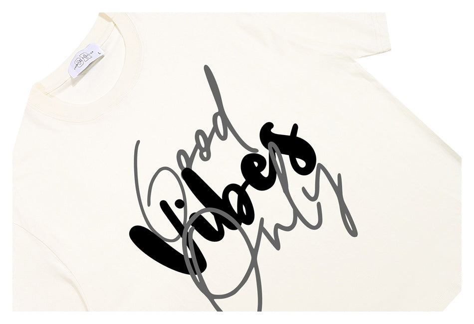 Close-up of an off-white T-shirt front with large overlapping black and gray script artwork.