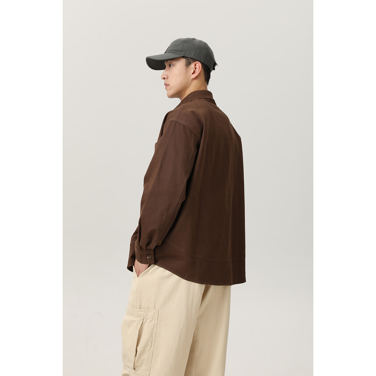Side and back view of a model wearing a dark brown shirt jacket with cream cargo pants.