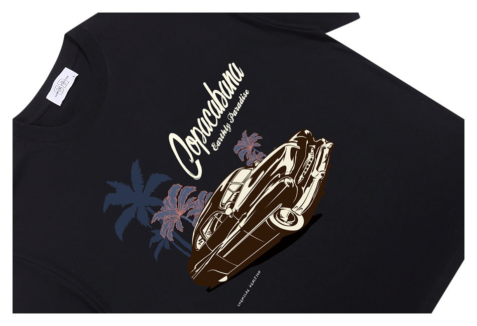 Angled flat lay of a black T-shirt with a cream and brown vintage car and palm tree graphic.