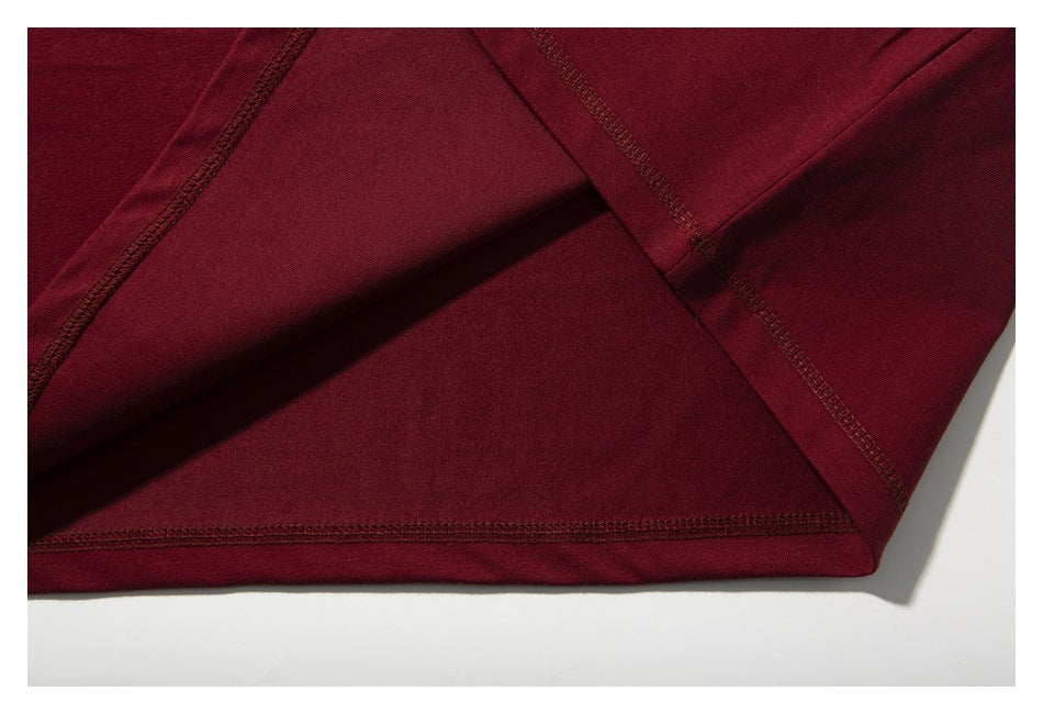 Close-up of the burgundy T-shirt's inside fabric and overlock stitching at the seams and hem.